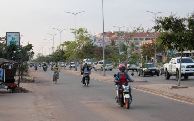 Siem Reap, Kamboçya, 17 Aralık 2018 mopedli insanlar bir şehir caddesinde gezintiye çıkıyor. Asya şehrinde tipik trafik. Şehir hayatı.