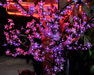 Yapay çiçekli ağaç. Küçük çiçekler, dekoratif ışıklar ile aydınlatılmış. Süs bitkisi.