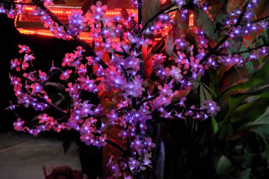 Yapay çiçekli ağaç. Küçük çiçekler, dekoratif ışıklar ile aydınlatılmış. Süs bitkisi.