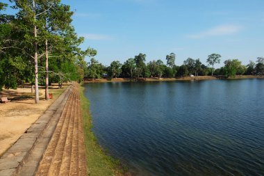 Kamboçya'daki antik kraliyet göletinin dolgusu. Kıyıda Ortaçağ taş binalar.