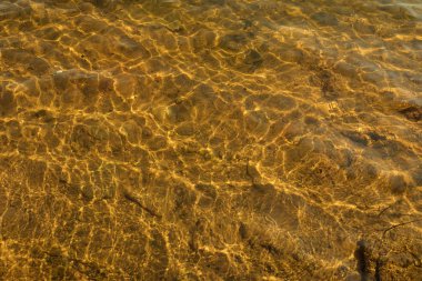 Sudaki dalgalanmalar. Su yüzeyi. Sudaki güneş parıltısı.