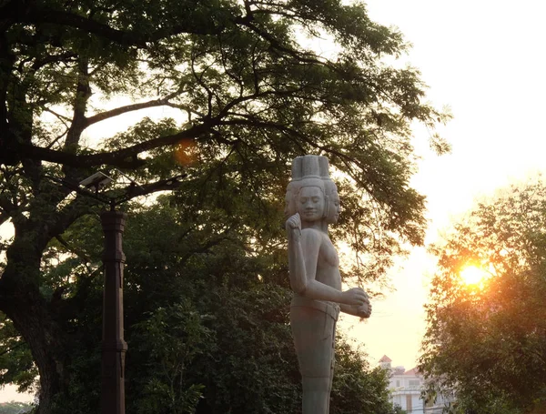 Sculpture of a Hindu deity in the rays of the setting sun. Statue in a city park.