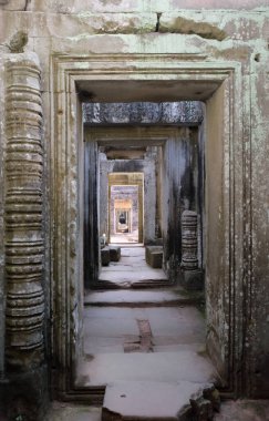 Harap olmuş eski bir binada uzun bir taş koridor. Boş kapı.