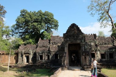 Ortaçağ terk edilmiş Preah Khan tapınağının girişinde turistler var..