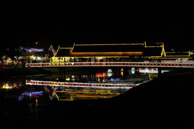 Dekoratif ışıklarla süslenmiş köprü küçük bir nehre atılır. Gece vakti..