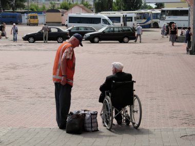 Chernihiv, Ukrayna, 7 Haziran 2019. Bir tren istasyonu çalışanı tekerlekli sandalyedeki yaşlı bir adamla iletişim kuruyor. Engelli yolculara yardım.