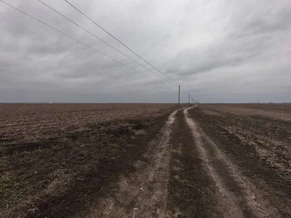 Power lines along a dirt road. Gloomy evening landscape.