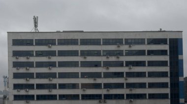 Bulutlu bir günde ön cephesinde bir sürü kliması olan çirkin ofis binası..