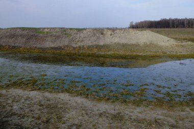 Kuru bir gölün dibi. Sığ bir su kütlesi. Yapay bir göletin kıyısında dik bir yamaç..
