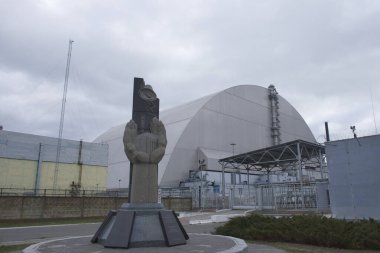 Pripyat, Ukrayna, 14 Mart 2020. Çernobil Nükleer Santrali 'ndeki kazayı tasfiye edenlerin anıtı koruyucu bir lahitin arka planında..