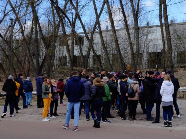 Çernobil, Ukrayna, 14 Mart 2020. Terk edilmiş eski bir binanın önünde büyük bir turist grubu. Farklı yaş ve cinsiyetlerden insanlar. Yasak bölgede gezginler.