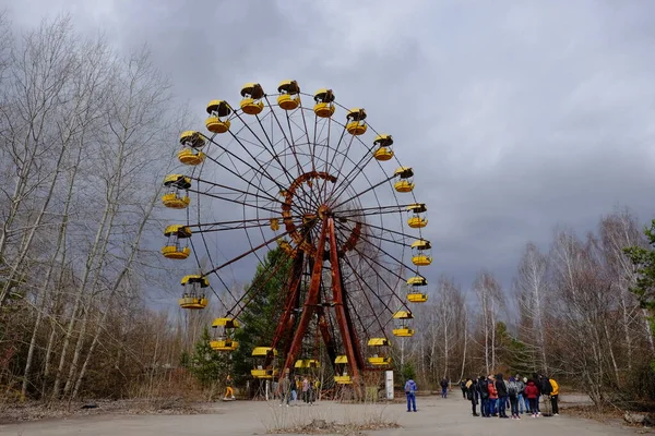 Pripyat, Ukrayna, 14 Mart 2020. Pripyat 'ta terk edilmiş bir lunaparkta ünlü dönme dolabın yanındaki turistler. Bulutlu hava, gökyüzü bulutlarla kaplı..