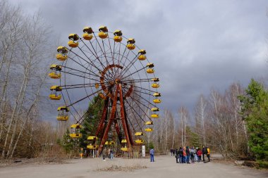 Pripyat, Ukrayna, 14 Mart 2020. Pripyat 'ta terk edilmiş bir lunaparkta ünlü dönme dolabın yanındaki turistler. Bulutlu hava, gökyüzü bulutlarla kaplı..