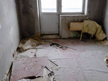 Escalier duvarlardan gevşemiş. Terk edilmiş bir apartmanın zemininde bir yığın çöp. Pislik ve yıkım..