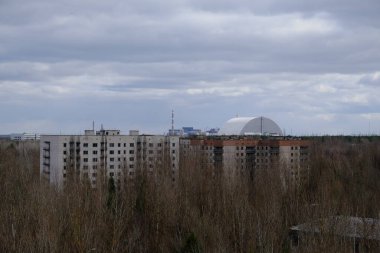 Pripyat 'ta terk edilmiş evler. Arka planda Çernobil nükleer santrali ve koruyucu lahit var..