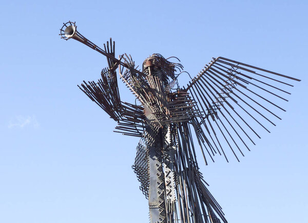 Чернобыль, Украина, 14 марта 2020 г. Металлическая скульптура трубящего ангела против голубого неба в Чернобыле. Памятник Чернобыльской ядерной катастрофе. Статуя третьего ангела.