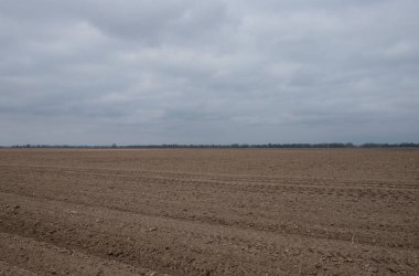 Tarlaya sürülmüş bir tarlanın üzerindeki güzel gökyüzü. Tarım endüstrisi manzarası. Tarlaya sürülmüş bir çiftlik. Gündüz ekili toprak.