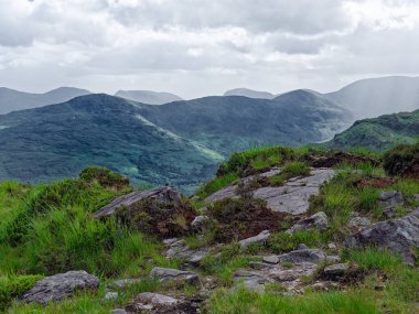 İrlanda 'daki görkemli dağ sırası. Dramatik bir gökyüzünün altındaki yemyeşil tepelerin ve vadilerin çarpıcı manzarası. Seyahat broşürleri için ideal.
