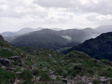 Sakin İrlanda manzarası, yuvarlanan yeşil tepeler bulutlu bir gökyüzü ile buluşuyor, nefes kesici bir manzara sunuyor. Seyahat veya doğa belgeselleri için mükemmel..