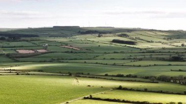 Aerial view of green patchwork fields in West Cork, Ireland, during the daytime revealing the Irish countryside.