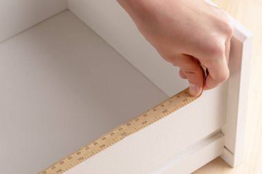 Genç bir adam bir başucundaki kat etmeye çalışıyor. Bu raflar bir ölçme aracı ile ölçer.