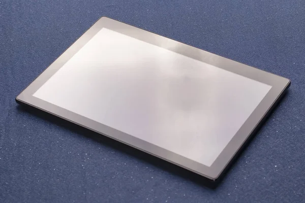 Illuminated black digital tablet on blue cloth sheets