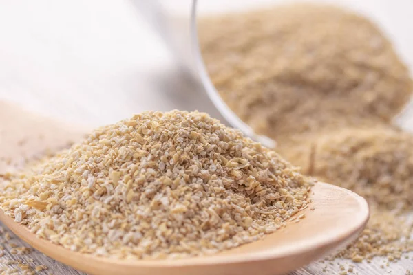 Yulaf kepeği bir tahta kaşık ve saydam bir cam bir beyaz tahta masada. Sağlıklı beslenme, diyet ve uzun yaşam-in tüm aile kavramı.