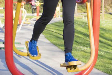 Genel bir parkta egzersiz donanımları ile eğitim genç kadın. Beyaz çiçekli arka plan yeşil çim. Hamilelik sonrası kurtarma rakamlar kavramı