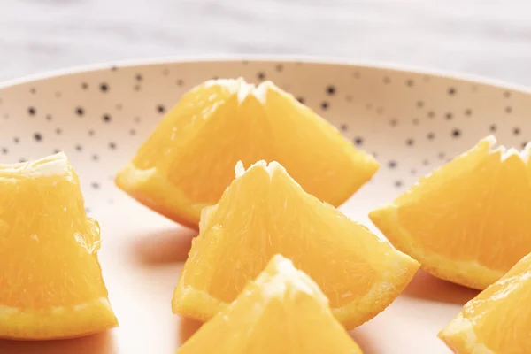 Freshly sliced oranges on a dotted brown plate. Macro with selective focus. The concept of ecological nutrition