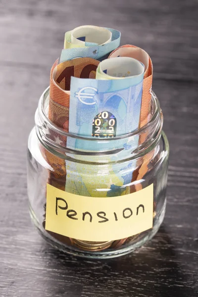 Cam Kavanoz sikke ve euro ile bir yazıt emeklilik siyah ahşap bir masa üzerine notlar ile. Zengin yaşlılık için mali tasarruf kavramı