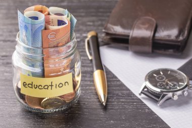 Cam Kavanoz sikke ve eğitim kelimelerle euro banknot ile. Kalem, kağıt, m-cüzdan ve bilek seyretmek boş sayfa. Özel ders ve kurslar için zamanında yapılan ödeme kavramı