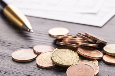 Euro euro sikkeleri üzerinde eski siyah ahşap masa yığını. Kalem ve numaraları ile Muhasebe belgeleri. Ödeme planlama faturalar