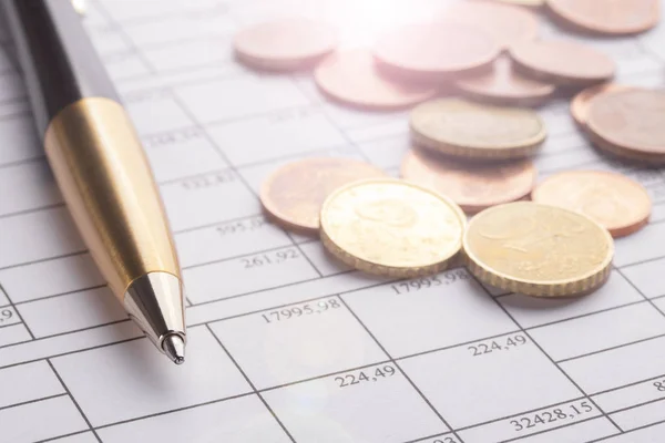 Montón de monedas en euros en la vieja mesa de madera negra. Pluma y documentos contables con números — Foto de Stock