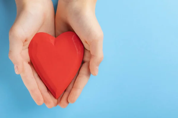 Elinde kırmızı bir ahşap kalp onların elinde tutan bir genç çocuk. Mavi arka plan