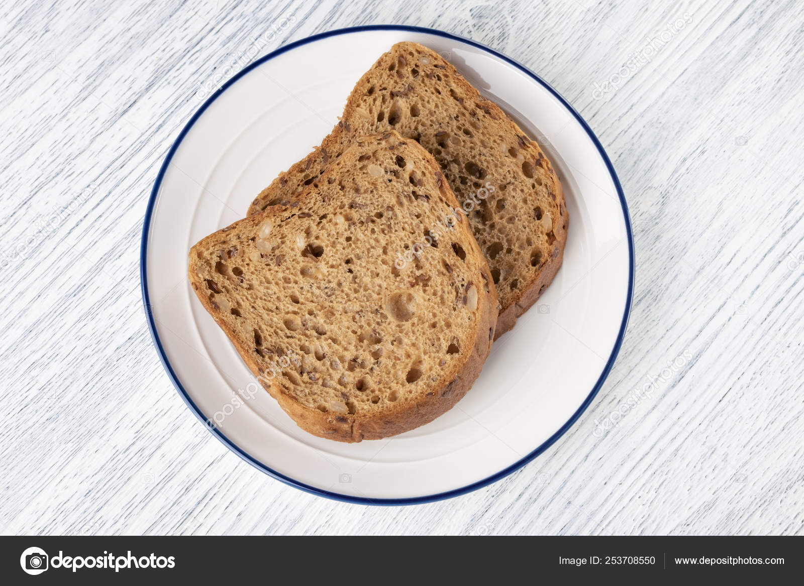 Slices Of Grain Bread With Mold On A White Plate With A Blue Stripe
