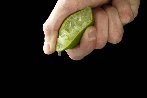 Bir adamın elini yarım limon suyu sıkar. Sulu damla aşağı asılı.