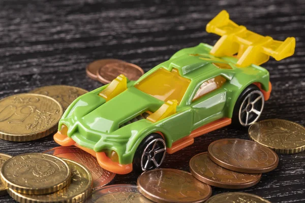 Car toy and euro coins on a dark wooden background.