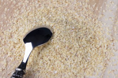 Bir metal kaşık ile ahşap bir arka planda ezilmiş buğday tohumları