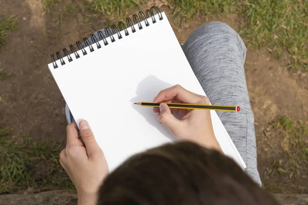 Il ragazzo sta per disegnare una matita nera e gialla in un quaderno aperto — Foto Stock