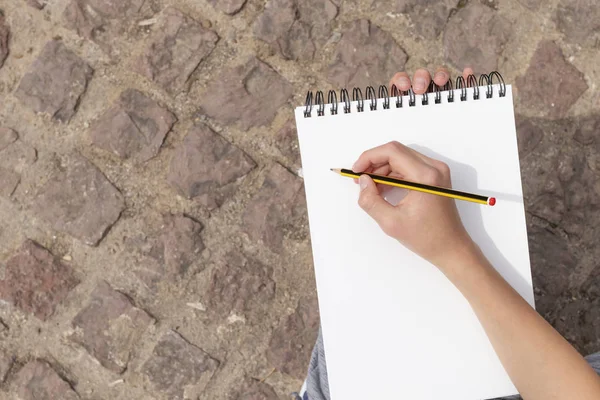 Parkta açık bir not defteri üzerinde bir kalem ile çocuk eli.