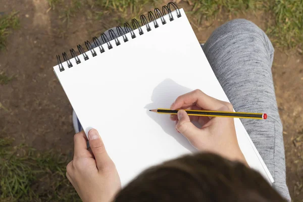 Il ragazzo sta per disegnare una matita nera e gialla in un quaderno aperto — Foto Stock