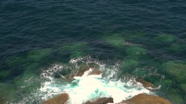 晴れた晴れた日に岩の海岸で泡立つ波が壊れる — ストック動画