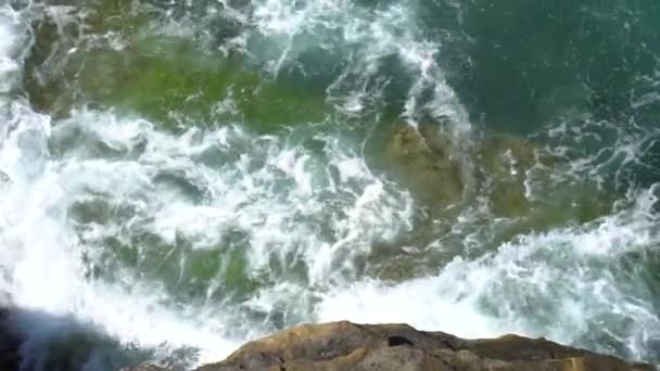 Foamy waves break on a rocky shore on a sunny, clear day — Stock Video