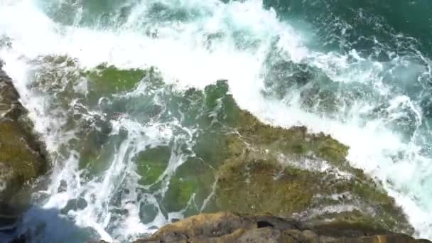 Foamy waves break on a rocky shore on a sunny, clear day — Stock Video