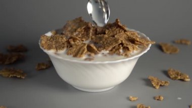 Bir adam gri bir arka plan üzerinde beyaz bir tabak diyet süt ile yulaf ezmesi bir kaşık karıştırır. Doğal ürünlerden yapılan sağlıklı kahvaltı pişirme. Yavaş çekim