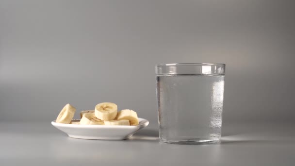 Plátanos Rodajas Plato Blanco Sobre Fondo Gris Enloquecido Con Agua — Vídeos de Stock