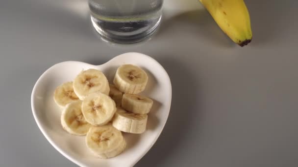 Φέτες Και Ολόκληρες Μπανάνες Λευκό Πιάτο Γκρι Φόντο Misted Καθαρό — Αρχείο Βίντεο