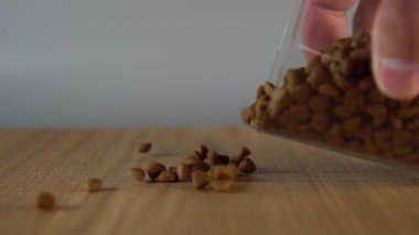 Bir adam el bir cam bardak ahşap bir yüzeye gevrek kuru kedi maması serpiştirir