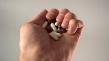 El gri bir arka plan üzerinde avuç içinde kahverengi ve beyaz tıbbi kapsül karışımları