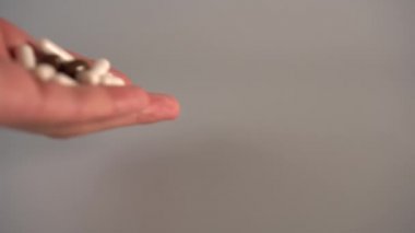 El gri bir arka plan üzerinde çok renkli tıbbi kapsül bir avuç dışarı dökülür. Uyuşturucu ile kilo verme kavramı